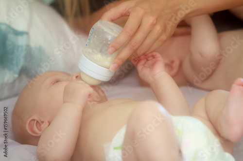 indoor portrait of young happy smiling mother with twin babies at home