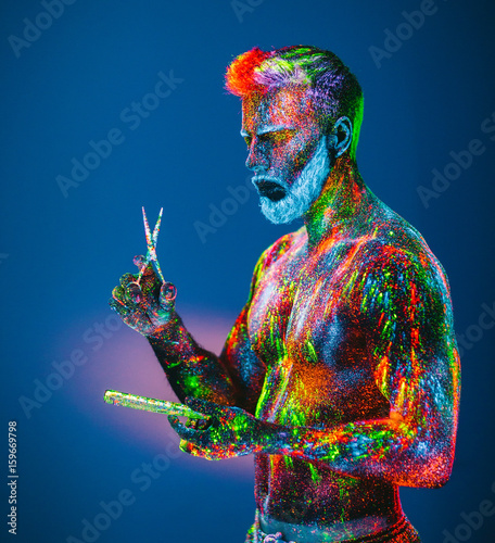Concept. A bearded man in Barbershop. A stylish bearded man is trimmed  in Barber Shop. The man is decorated in ultraviolet powder. photo