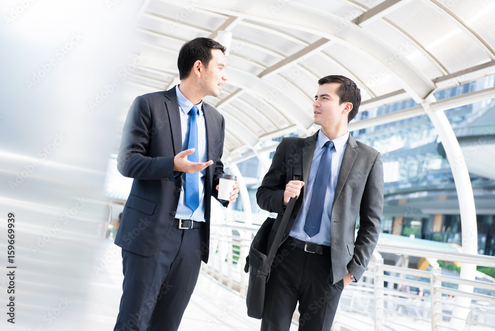 Interracial businessmen as colleague, walking and talking in the morning Interracial businessmen as colleague, walking and talking in the morning