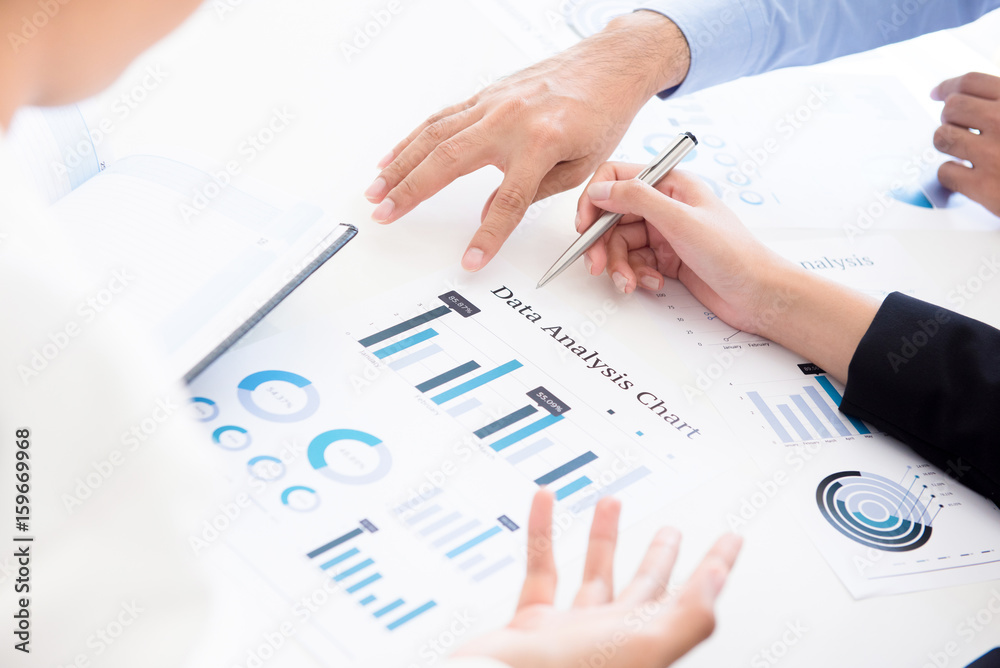 Business people discussing data analysis chart document Business people discussing data analysis chart document