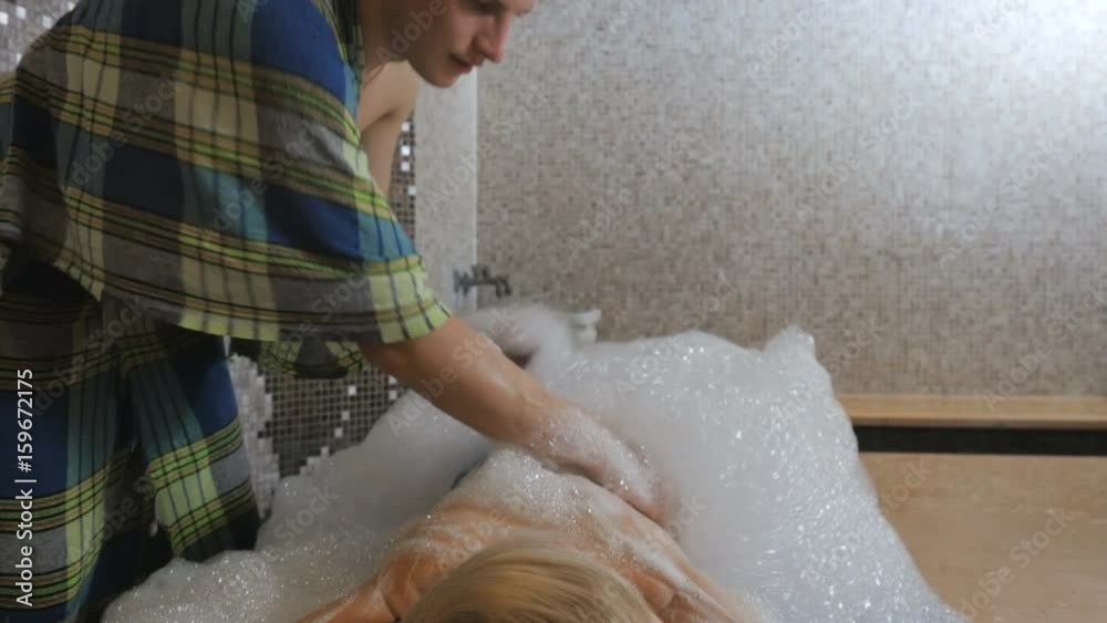 Handsome man massaging with foam a girl's back in the Turkish bath Handsome man massaging with foam a girl's back in the Turkish bath