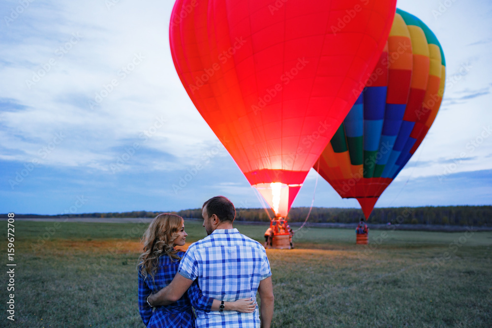 Beautiful romantic couple hugging at meadow. hot air balloon on a ...