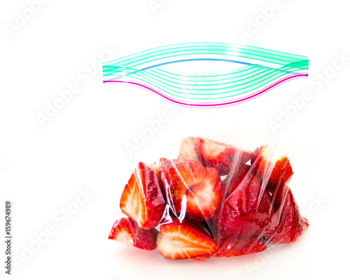 Studio shot fresh chopped strawberries in clear open plastic bag with lock isolated on white. In-house cut, packed strawberry in transparent zipper bags to-go/take away. Convenience, healthy lifestyle