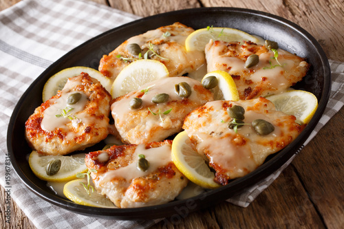 Italian traditional food: chicken piccata with lemon, thyme and capers close-up. Horizontal