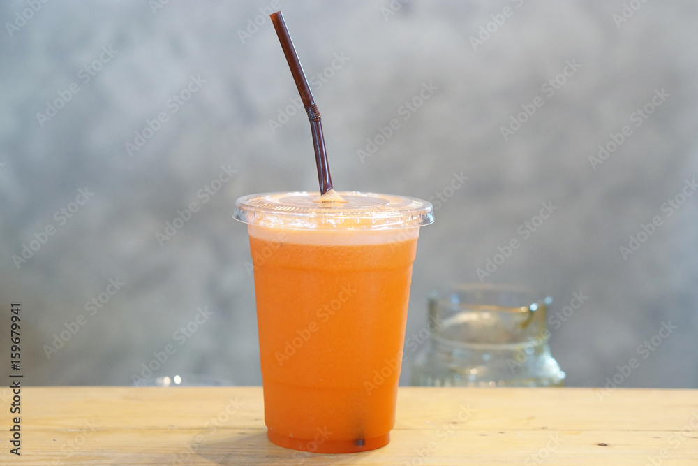 Closeup plastic glass of cold pressed juice on wooden table, Fresh mixed fruits, Healthy drink concept. Closeup plastic glass of cold pressed juice on wooden table, Fresh mixed fruits, Healthy drink concept.