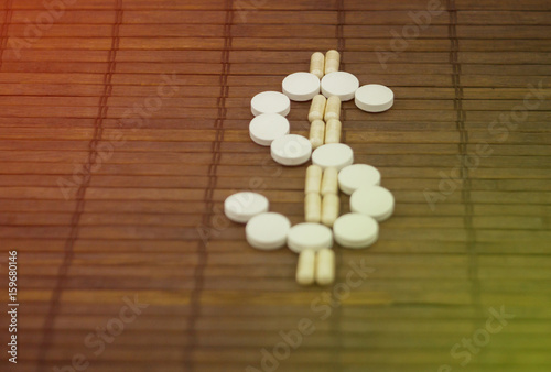 Emblem of dolor  lined with round tablets on a dark wooden background