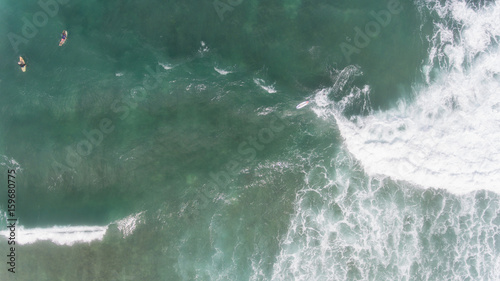Aerial view of Surfer swimming on board near huge blue ocean wave