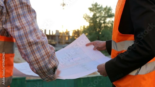 Two construction engineers on the construction site inspect the drawings photo