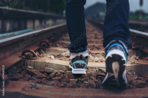 lifestyle image of man legs wear sport shoes walk on railway track 