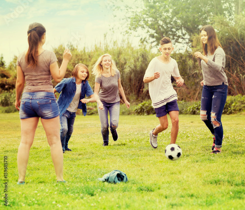 Group of carefree teenagers kicking football