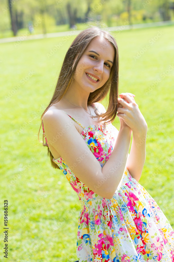 Portrait of young beautiful woman with long hair wearing flower dress in green spring park Portrait of young beautiful woman with long hair wearing flower dress in green spring park