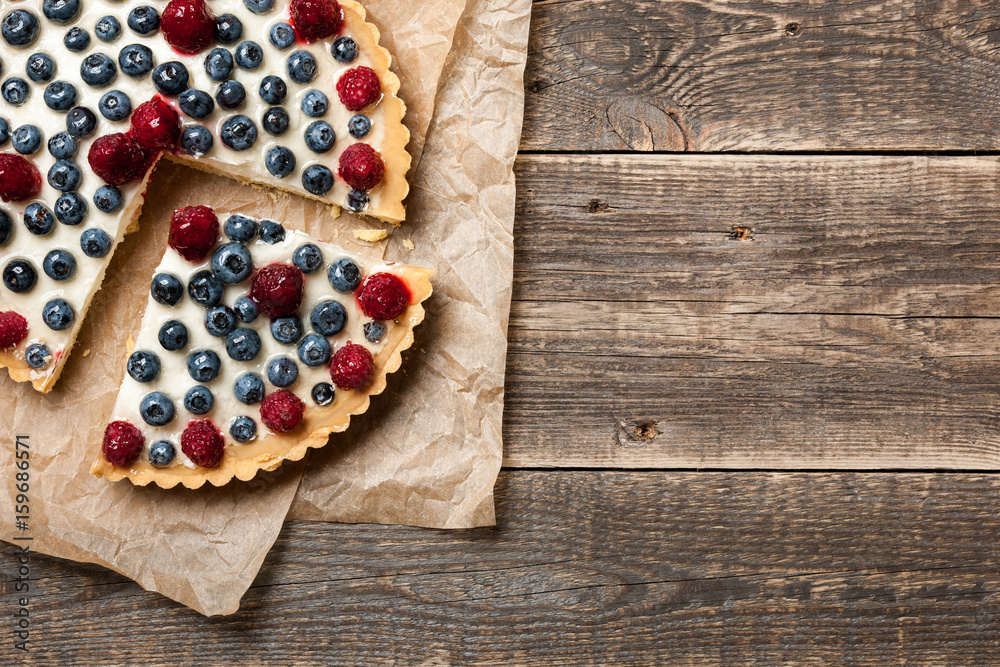 Tartlet cake with raspberries and blueberries on wooden table