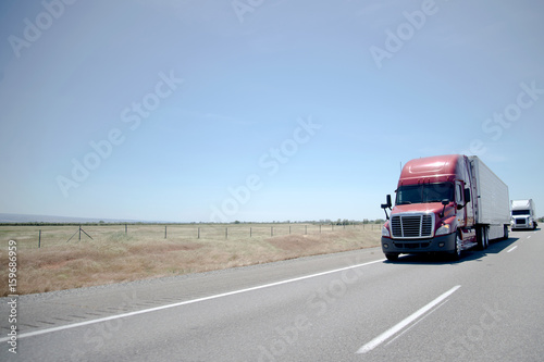 Semi trucks convoy on straight highway on flat plateau