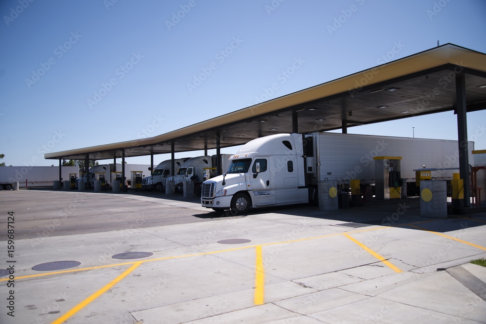 Semi Trucks with trailers are at filling station for diesel refueling