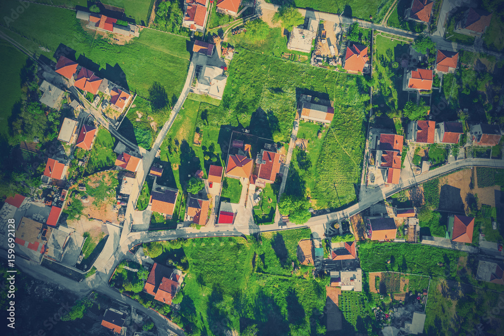 Top view of the village houses with red tiled roof on the green grass. Toned