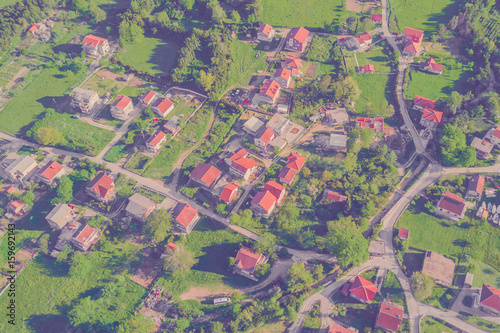 Top view of the village houses with red tiled roof on the green grass. Toned