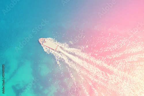 Top view of a boat floating on the blue sea in the sunlight