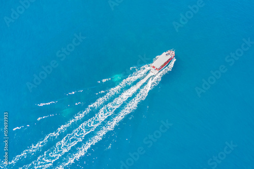 Top view of a white boat sailing in the blue sea © watman