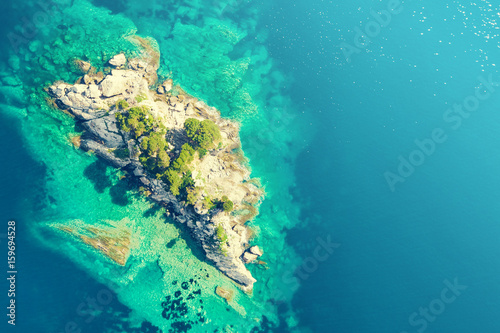 Top view of a rocky island with green trees in the sea © watman