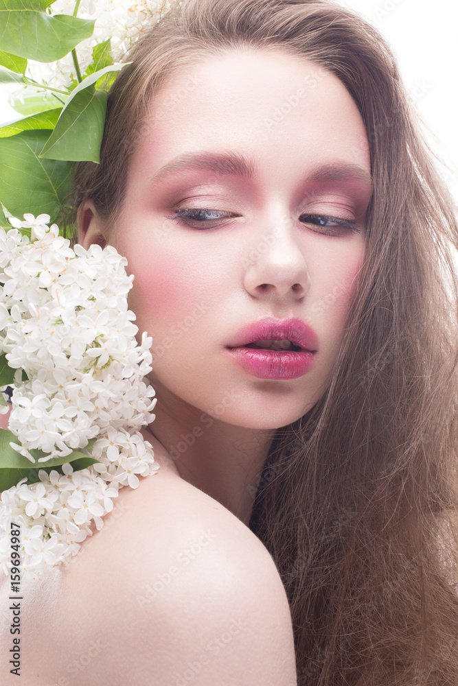 A young girl with lilac and bright creative make-up. Beautiful model with flowers and long hair. White isolated background. Pure shining skin. Beauty of the face. Spring picture. A young girl with lilac and bright creative make-up. Beautiful model with flowers and long hair. White isolated background. Pure shining skin. Beauty of the face. Spring picture.