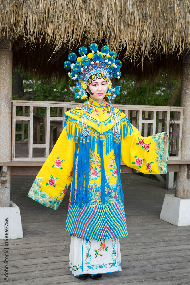 Fototapeta premium beautiful chinese girl in traditional chinese dress with long sleeves and hat standing outdoor