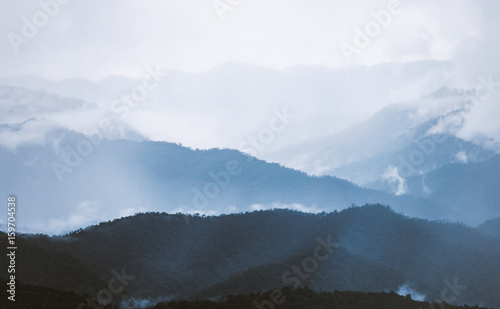 Foggy blue mountain with clouds and bright sky after raining of tropical forest on northern of Thailand.