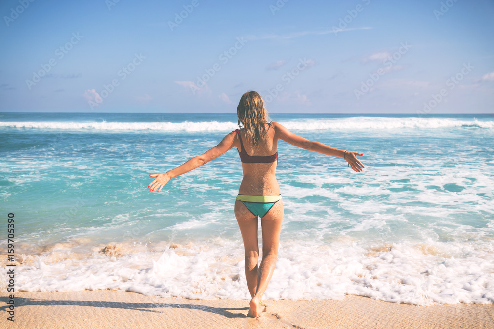 Woman on the tropical beach enjoying life with open arms.