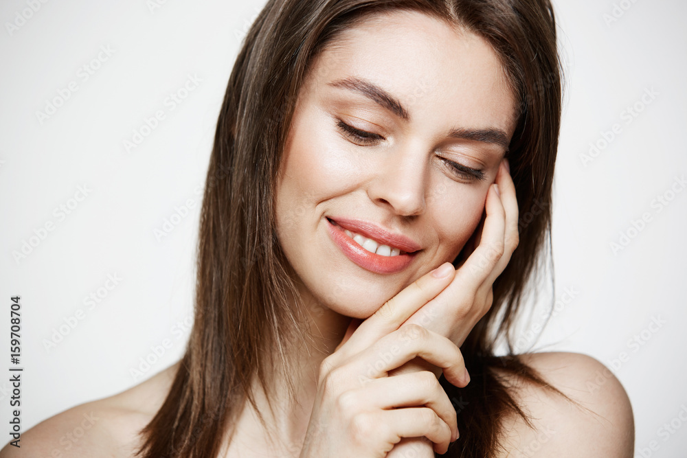 Portrait of young brunette beautiful girl smiling touching face over white background. Spa beauty healthy and cosmetology concept. Portrait of young brunette beautiful girl smiling touching face over white background. Spa beauty healthy and cosmetology concept.
