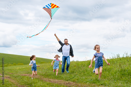 happy family father and children run with kite on meadow © JenkoAtaman