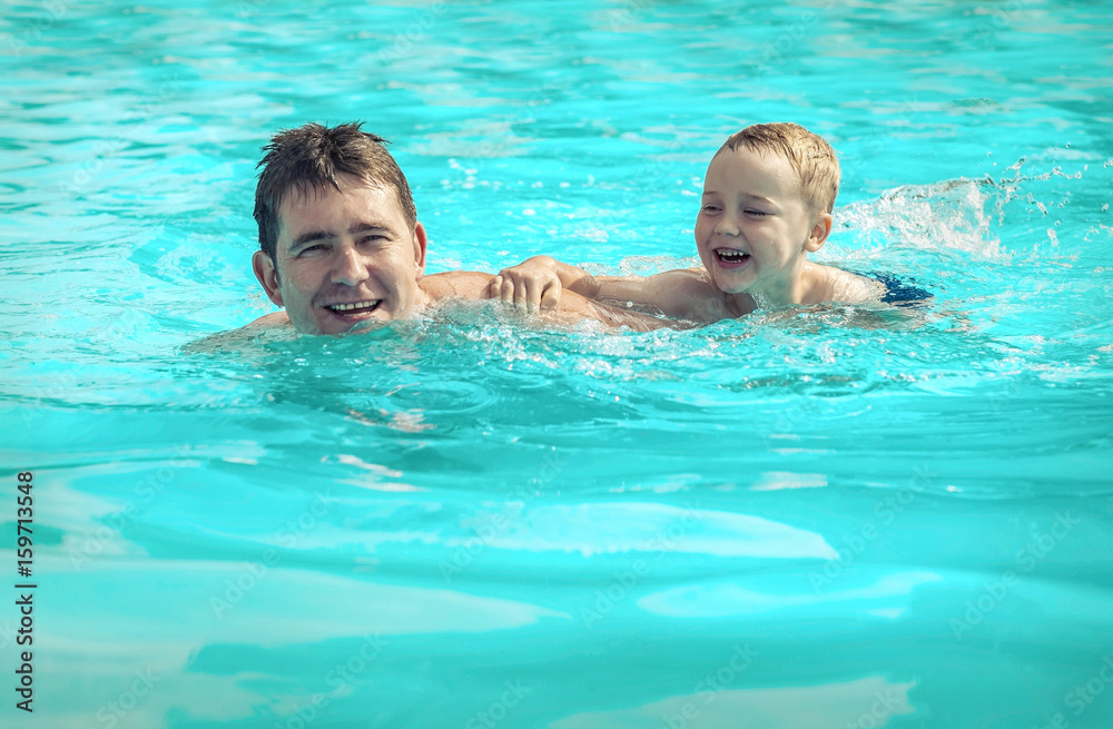 Father and son funny in  water pool under sun light at summer da