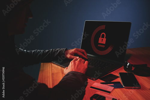 Unrecognizable person hacking laptop in the dark, breaking security system