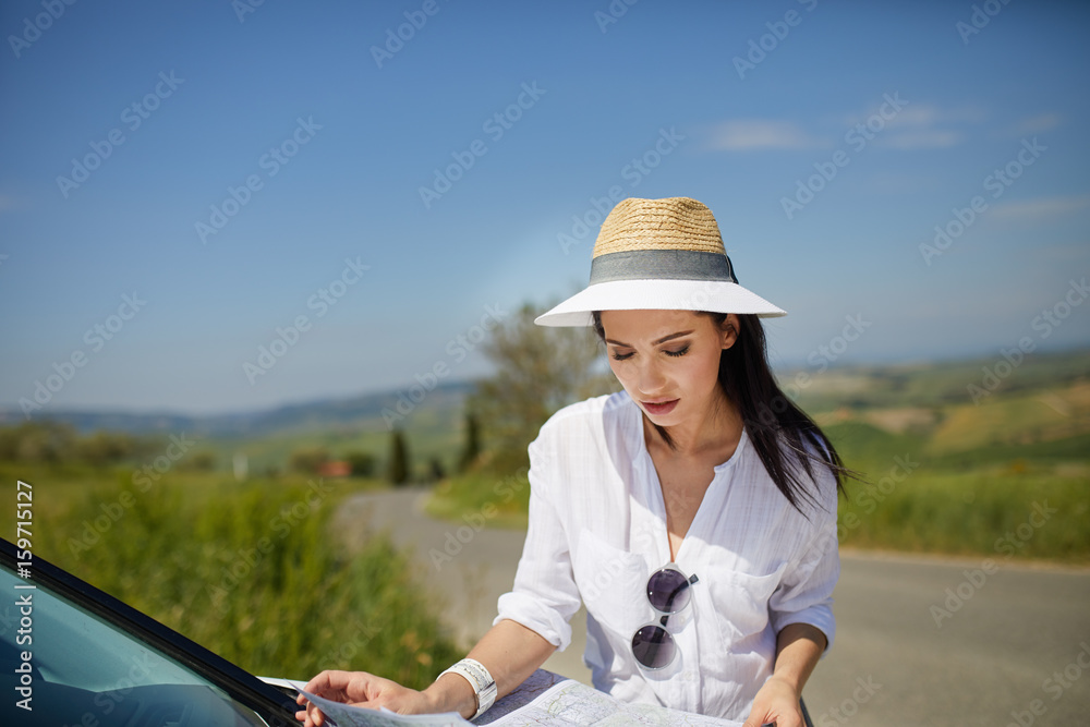 A tourist with a map at the car checks the route to the destination