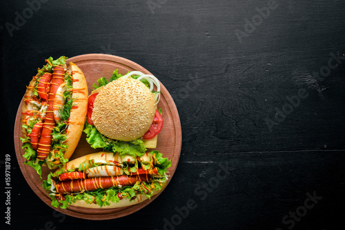 Quadro su tela Hot dog and hamburger with cheese, meat and greens on Wooden background