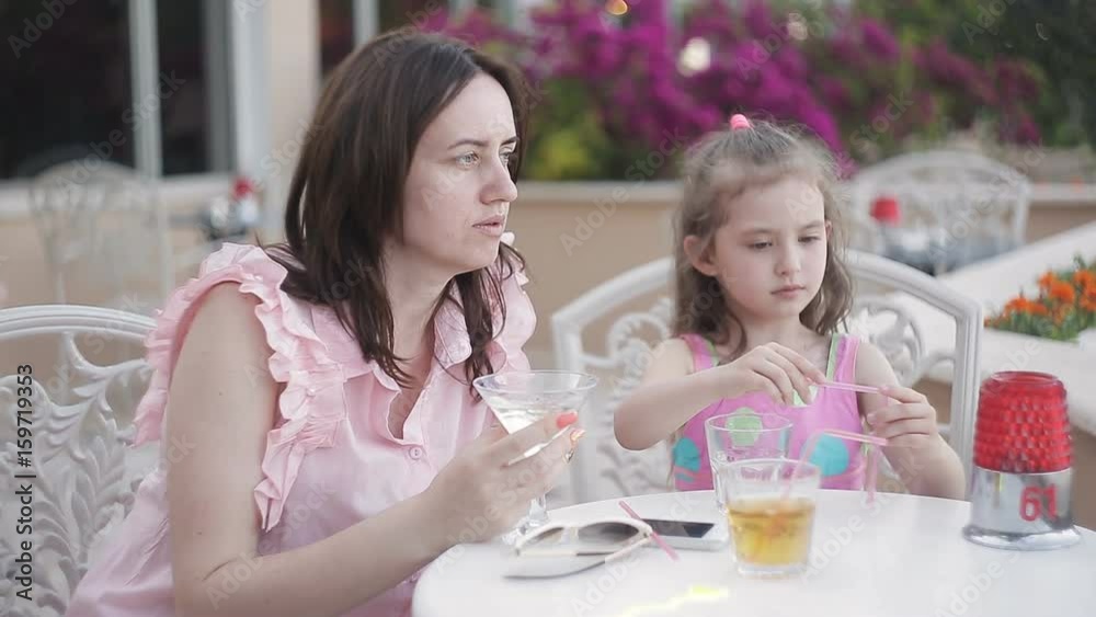 Mom with two daughters in a cafe on vacation to drink juice and talk Mom with two daughters in a cafe on vacation to drink juice and talk