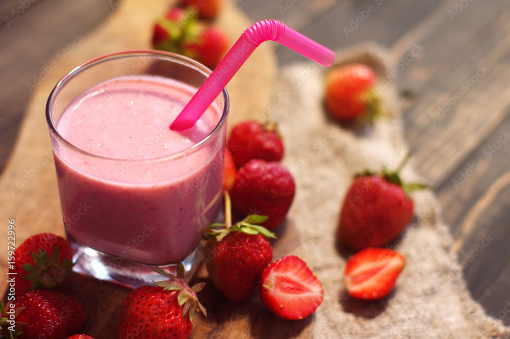 Milkshake with strawberry berries. Strawberry smuz in a glass with a tubule on a wooden board Milkshake with strawberry berries. Strawberry smuz in a glass with a tubule on a wooden board
