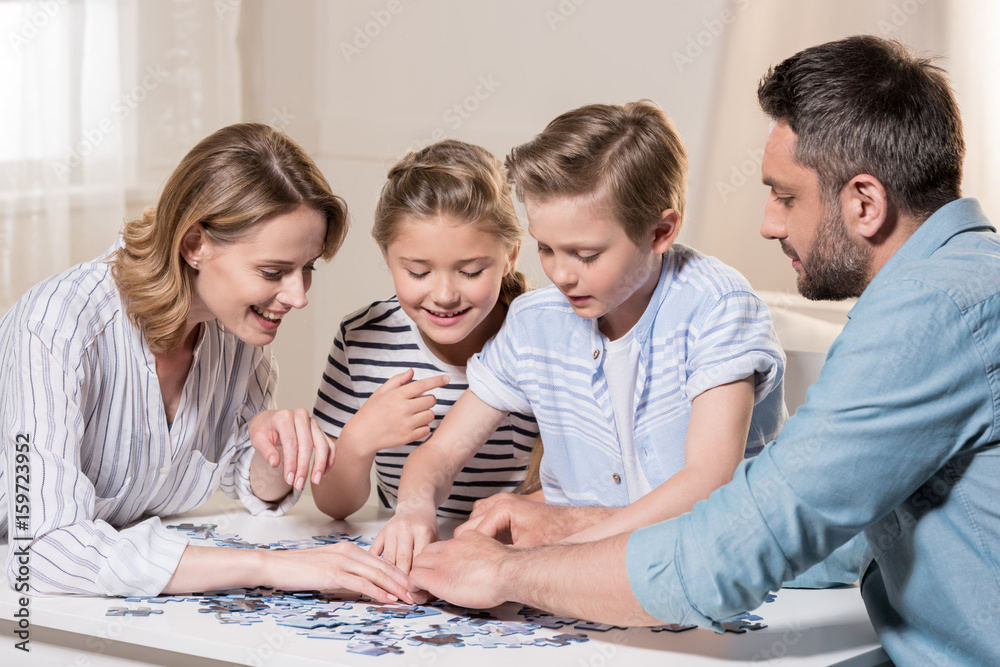 smiling family playing with puzzle on table at home together smiling family playing with puzzle on table at home together