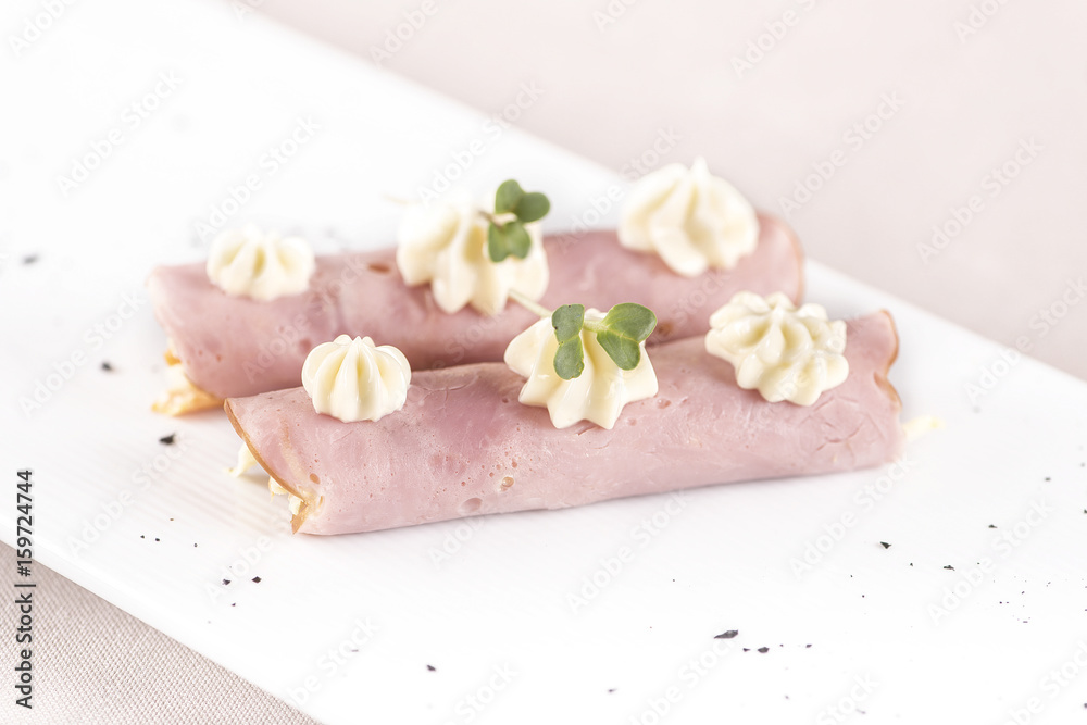 Fresh appetizer with ham and Coleslaw salad, decorated with mayonnaise and green leaf, placed on white plate, light background, isolated