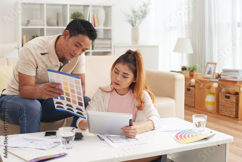 Portrait of young Asian couple choosing colors while planning new house design