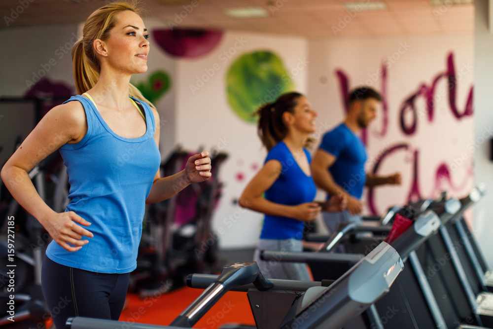 Young woman warming up on treadmill at gym