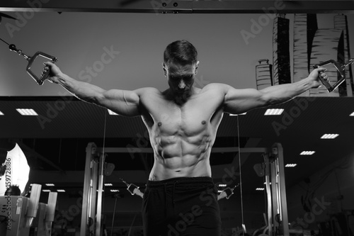 Male fitness model with naked torso posing in gym