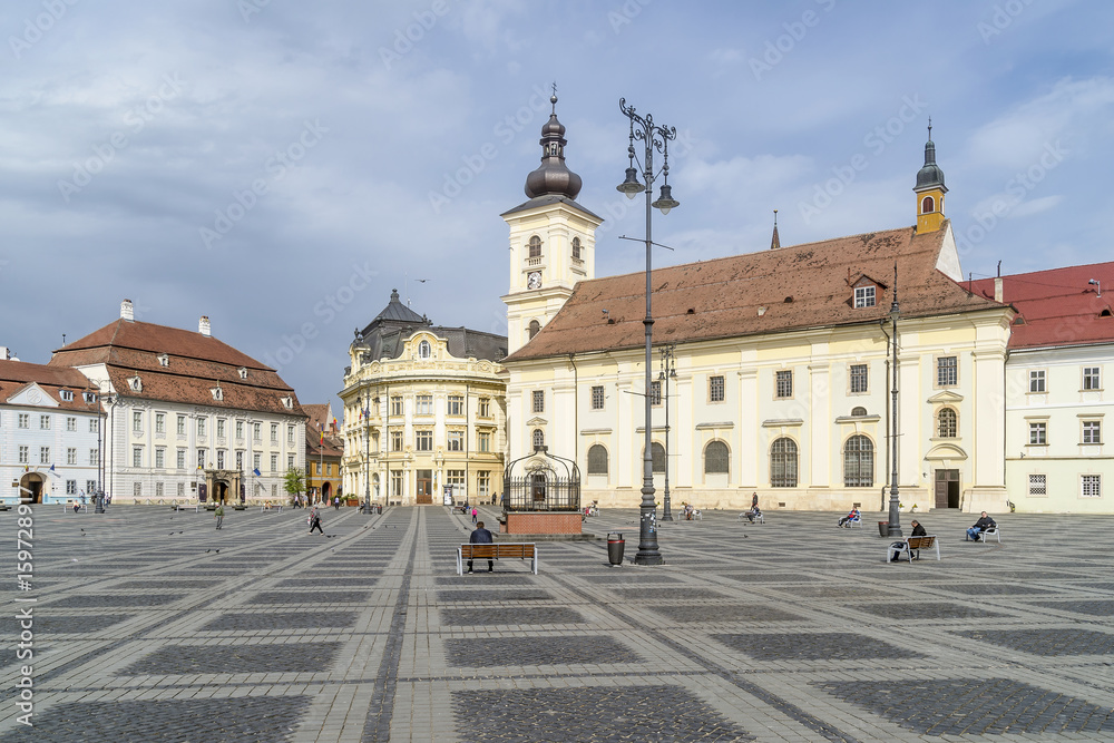 Benches on the famous Piata Mare, Large Square, in a moment of tranquility, Sibiu, Romania, with the Holy Trinity church in the background