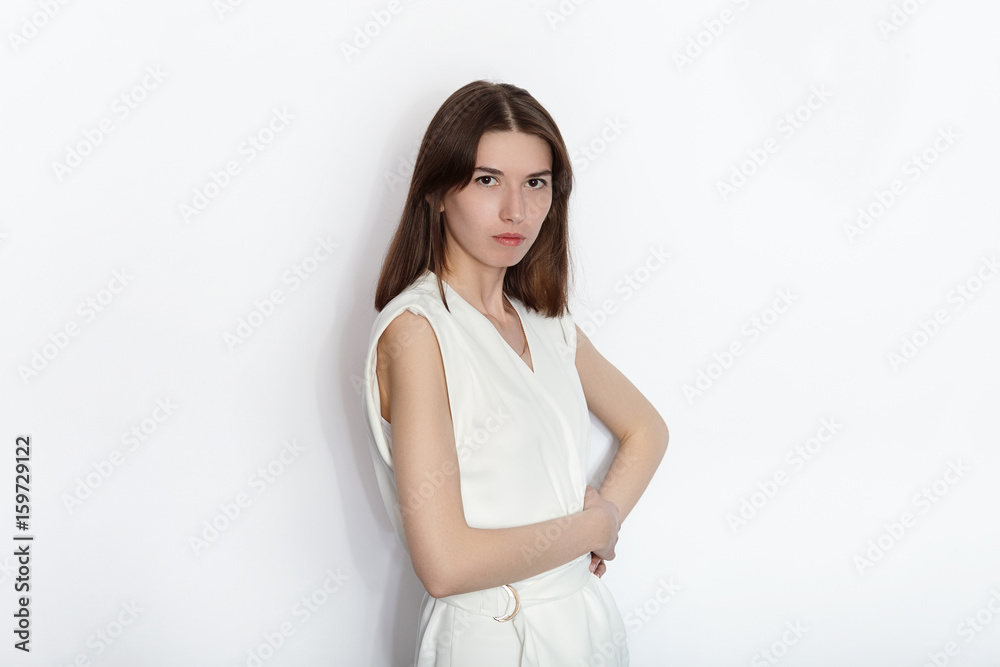 Young beautiful brunette beginner model woman in white blouse practicing posing showing emotions on white wall studio background Young beautiful brunette beginner model woman in white blouse practicing posing showing emotions on white wall studio background