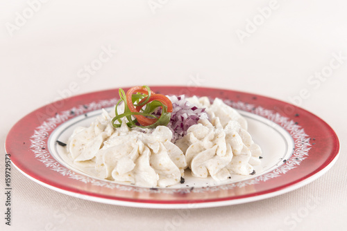 Fish roe salad, whit toasted bread, onion, green leafs, lemon, radish and olives, placed on a white plate, brown background