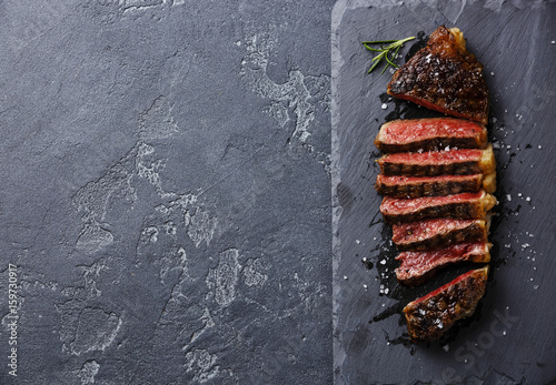 Sliced medium rare grilled Striploin steak on slate board copy space