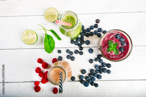 Blueberry, spinachy and orange smoothie on a wooden white background. Glasses of smoothie with berry and mint. Berry, leaf and lime, raspberries on a table. Fruit Healthy food. Breakfast.