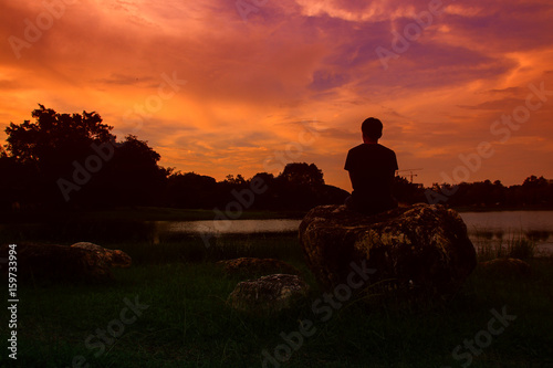 Silhouette of man meditating and yoga practicing with exercise at  sunrise in the morning.