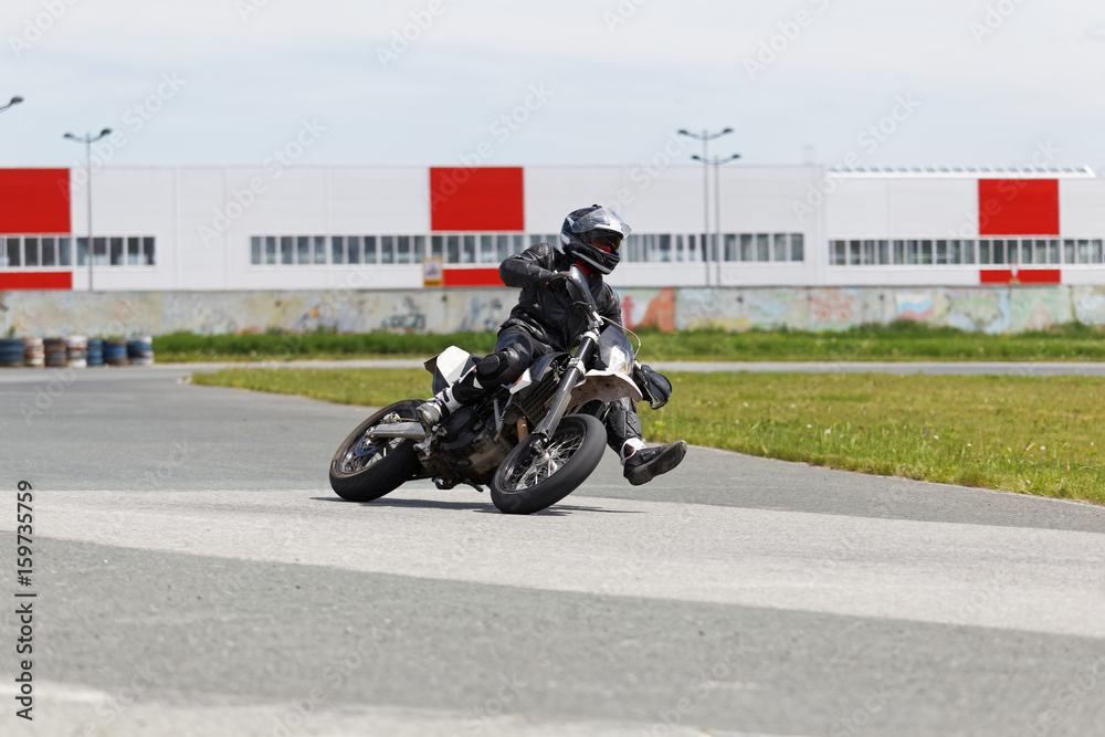 Motorcycle racer in black uniform leaning into a fast corner on track