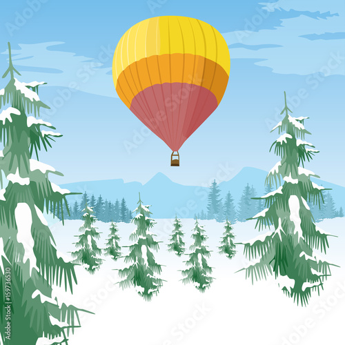 Air balloon flying over coniferous forest in a snowy valley
