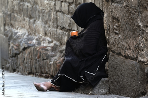 Poor woman begging sitting in the street. Empty copy space for Editor's text. photo