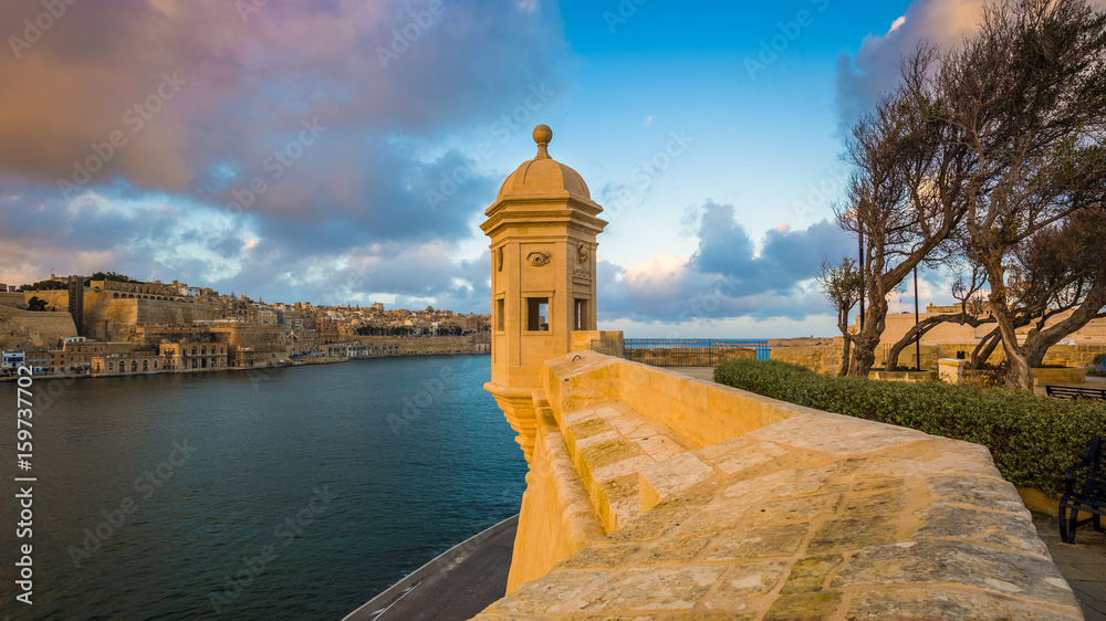 Senglea, Malta - Watch tower of Fort Saint Michael, Gardjola Gardens with the city of Valletta and beautiful sky and clouds at sunset